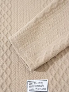 Close-up detail of beige knitted pullover showing diamond texture and sleeve cuff