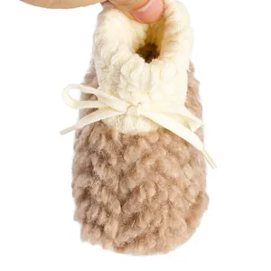 Macro view of plush winter baby sock shoe featuring a soft white fleece collar and bow
