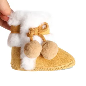 Détail de bottines d'hiver pour bébé en daim jaune avec fourrure blanche et pompons