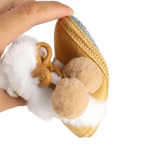 Détail de bottes d'hiver souples pour bébé avec fausse fourrure et pompons montrant la semelle