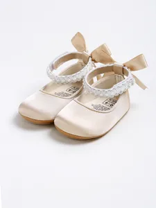 Detailed view of elegant cream satin baby princess shoes with pearl straps and bows