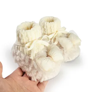 Close-up view of soft cream plush baby winter booties with elegant mesh bow detail