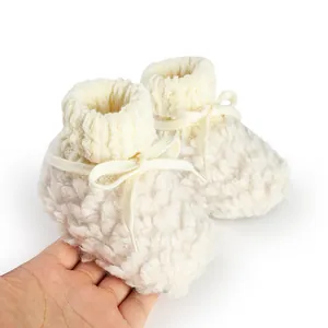 Detailed view of cozy off-white plush baby winter booties with ribbed knit cuffs and bow