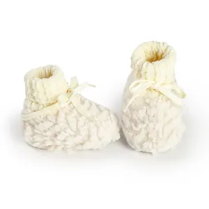 Cream fuzzy baby booties with ribbed knit collar and bow detail for winter warmth