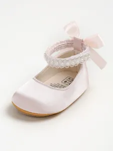 Detail of pink satin baby princess shoe with pearl strap and bow detail