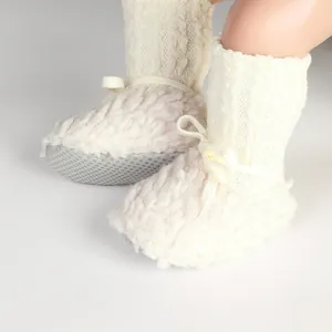 Close-up of cozy cream-white fleece baby pre-walker shoes with cable knit ankle bows