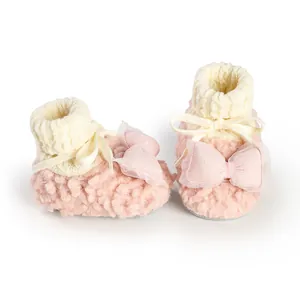 Detailed view of pink fuzzy baby shoes with a soft white knitted collar and cute bow accents