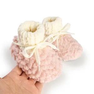 Close-up of soft pink winter fleece baby booties with knitted cuffs and white laces