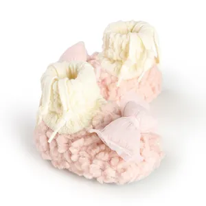 Close-up of pink fuzzy baby shoes with soft mesh bow and knit cuff detail