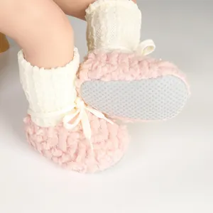 Close-up view of pink fuzzy baby walking shoes with white knit cuffs and non-slip soles