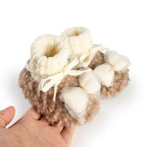 Detail of warm brown fleece baby booties with cream knit cuffs and mesh bows