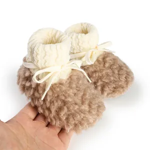 Close-up of cozy fleece-lined baby booties with knitted cuffs and bow tie