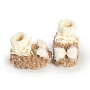 Detailed view of fleece-lined baby winter booties with cream bows and knitted cuffs.