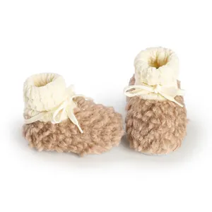 Soft fuzzy brown baby winter booties with white knit cuff and decorative bow detail