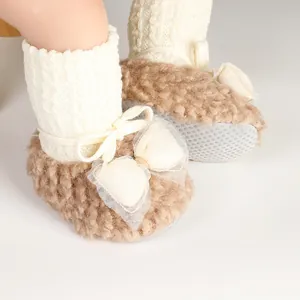 Detail view of plush baby winter sock shoes with decorative bow and non-slip sole