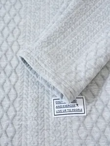 Detailed macro view of gray quilted fabric texture and sleeve patch on sweatshirt