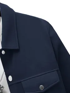 Detailopname van een donkerblauwe herenjas met zilveren drukknopen en een borstzakje