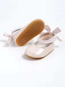 Detailed view of elegant beige baby princess shoes with pearl straps and silk bows.