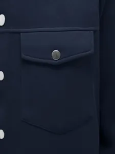 Detail van de borstzak op een marineblauw herenjack met metalen drukknoopsluiting.