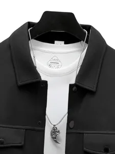 Détail rapproché des revers d'une veste noire ajustée pour homme avec collier à pendentif