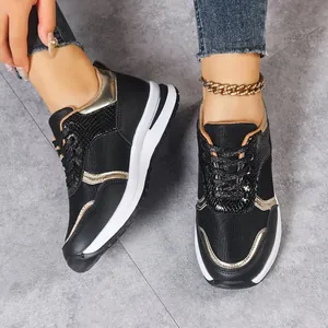 Vue détaillée des baskets compensées noires et dorées pour femmes avec design à lacets