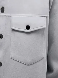 Détail d'une veste grise ajustée montrant la poche poitrine et le bouton pression.