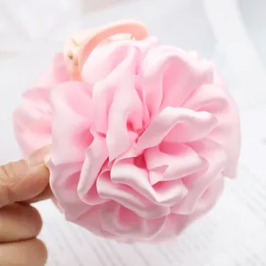 Close-up of pink satin rose flower hair claw clip showing fabric texture
