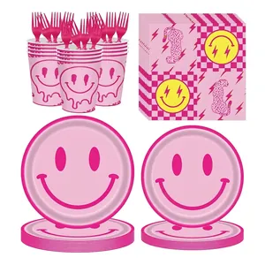 Set di stoviglie per feste rosa con faccine, tazze, tovaglioli e piatti di carta.