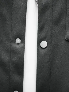 Détail des boutons-pression métalliques et de la texture du tissu côtelé d'une veste noire