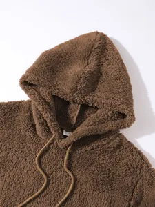 Detailansicht der braunen Plüsch-Fleece-Textur eines gemütlichen Herren-Kapuzenpullovers.