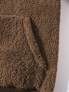 Nahaufnahme der weichen braunen Sherpa-Fleece-Stofftextur und des Taschendesigns