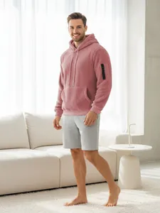Detailansicht eines Mannes in einem rosa Sherpa-Fleece-Hoodie im hellen Raum.