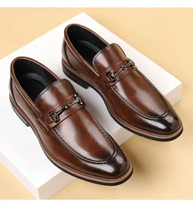 Close-up of brown leather men's dress loafers with metallic bit detail on white steps
