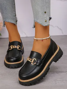 Detailed view of black British style loafers with gold chain and thick lug soles.