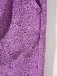 Detailed macro view showing the soft texture of purple fleece fabric on men's lounge pants