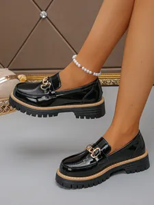 Close-up detail view of stylish black patent leather loafers with gold chain and chunky lug sole