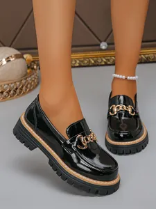 Close-up of black patent leather loafers with gold chain and thick platform sole