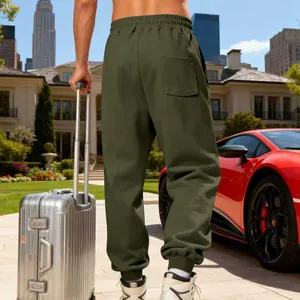 Back view of men's olive green fleece-lined sweatpants in a luxury outdoor setting