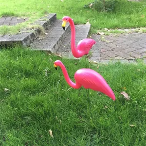 Set of two pink plastic flamingo garden ornaments standing on a green grass lawn