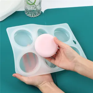 Primo piano di un sapone rosa tenuto sopra uno stampo in silicone per sapone a 6 cavità.