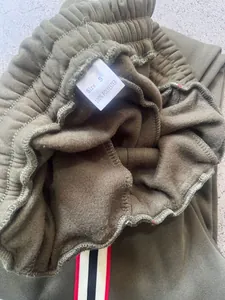Close-up of olive green fleece lining and wash label on men's heavy sweatpants.