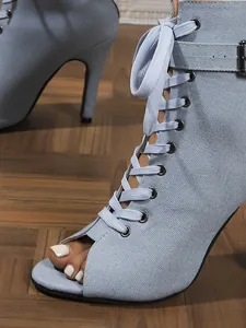 Close-up of light blue denim lace-up peep toe high heel sandal boots with buckle detail