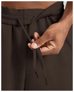 Detailed macro shot of the elastic waistband and adjustable drawstring on brown men's sports joggers