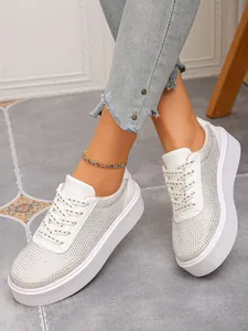 Stylische weiße Plateau-Sneaker mit glitzernden Strasssteinen am Fuß getragen