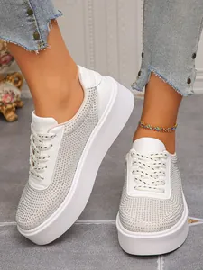 Detailansicht weißer Damen-Sneaker mit Plateausohle und schimmerndem Strassnetz.