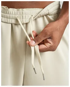 Close-up of beige men's loose joggers showing elastic waistband and adjustable drawstring