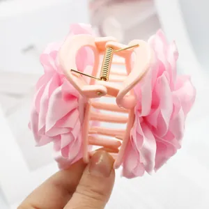 Detail view of pink satin peony flower hair claw clip showing silk petal texture