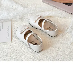 Close-up of white girls' bow princess shoes on a decorative lace background