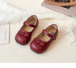 Detail of girls' maroon Mary Jane shoes with bow decoration and velcro strap closure.