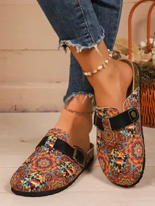 Ethnic print closed-toe clogs with adjustable buckle strap shown on model's feet